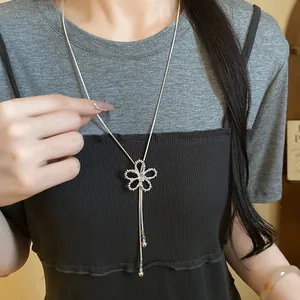 Detail of hollow flower zircon pendant necklace worn by a model as a sweater chain