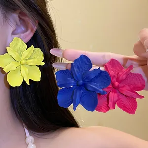 Detailed view of matte spray-painted flower stud earrings in yellow, blue and pink
