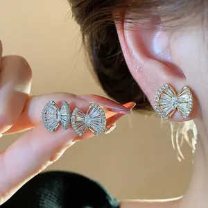 Detail shot of bow-shaped zircon stud earrings in 18k gold and silver plating