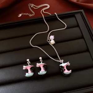 Macro detail of whimsical enamel apple core and kitten jewelry set with zircon accents