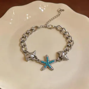 Bracciale a catena argento con ciondoli stella marina blu e conchiglia stile mare.