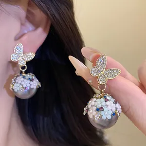 Exquisite detail of diamond-encrusted butterfly flower pearl drop earrings on model ear