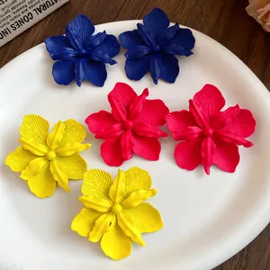 Close-up of matte spray-painted flower stud earrings in blue, red, and yellow