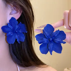 Close-up of vibrant blue oversized flower earrings with spray paint matte finish