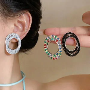 Detailed macro view of oval hollow stud earrings featuring white, multi and black zircons