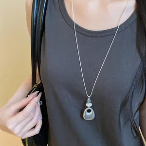 Minimalist long sweater chain with matte silver teardrop pendant shown on model