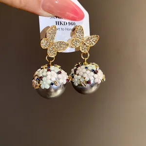 Close-up macro shot of elegant butterfly and multicolored floral pearl dangle earrings