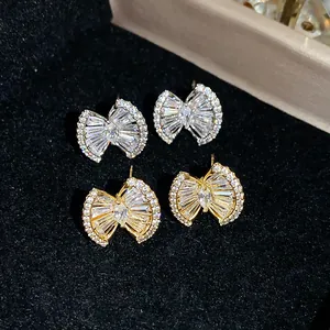 Detailed macro view of 18k gold plated bow stud earrings with sparkling baguette zircons.