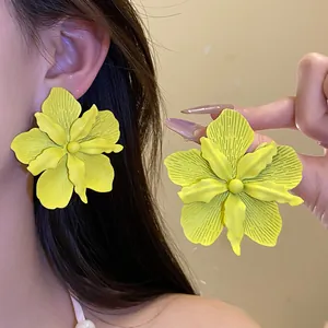 Detail of yellow matte flower stud earrings worn on ear showing oversized floral design.