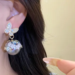 Detailed close-up showing silver needle butterfly earrings with floral pearl drops