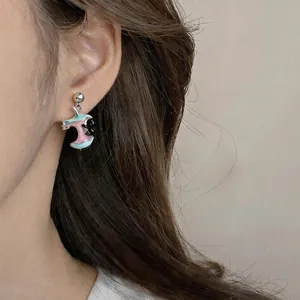 Close-up detail of a cute drip-glaze apple core and black cat earring on an ear.