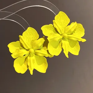 Exquisite detail of vibrant yellow painted orchid flower earrings with matte texture
