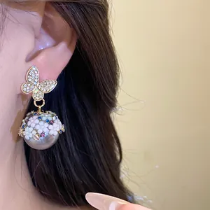 Detail of S925 silver needle earrings with rhinestone butterfly and flower pearl design