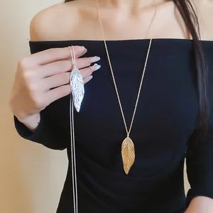Detailed view of gold and silver large leaf pendant necklaces worn by a female model