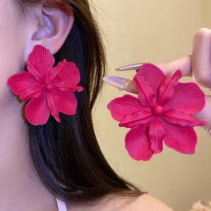 Detailed macro view of oversized matte fuchsia flower earrings worn by an Asian model