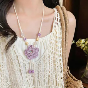 Detailed view of handmade woven purple flower necklace with beads worn by model