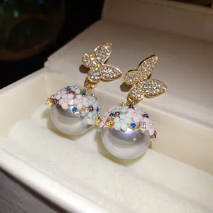 Close-up of butterfly flower pearl earrings with sparkling rhinestones and colorful details
