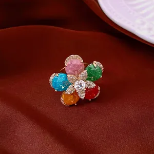 Close-up of a colorful 18k gold plated zircon flower-shaped open ring on dark fabric.