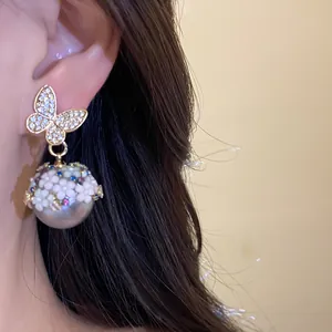 Detailed close-up of butterfly and pearl drop earrings with colorful floral accents
