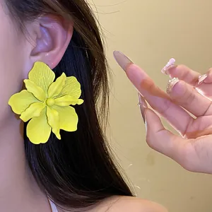 Vibrant yellow matte flower stud earring worn on ear, fashion accessory for women.