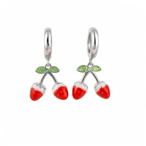 Pendientes de plata dulces con colgantes de fresa roja esmaltada sobre fondo blanco