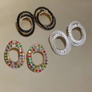 Detailed view of oval hollow earrings set with black, clear, and multicolor zirconia.