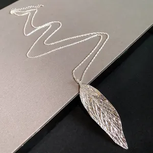 Close-up of a silver-toned large leaf pendant necklace with intricate vein texture