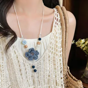 Close-up of boho woven flower necklace with wooden and ceramic beads on a model.