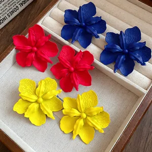 Detailed view of matte spray-painted flower stud earrings in red, yellow, and blue tones