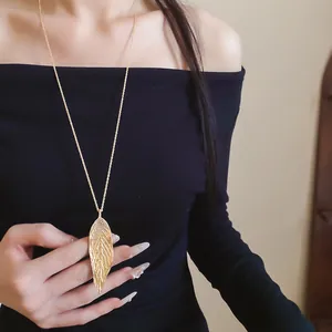 Detailed view of an elegant golden leaf pendant necklace worn by an Asian model