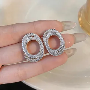 Detailed macro view of elegant oval hollow zircon stud earrings with silver needle.