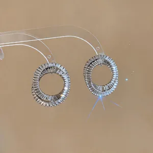 Close-up of silver needle interlocking oval hoop earrings with baguette zircons.