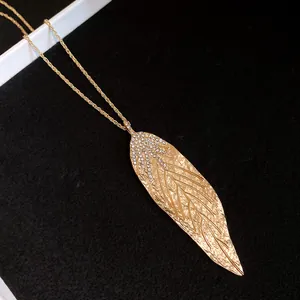 Detailed view of a minimalist gold-toned large leaf pendant necklace with rhinestone accents