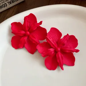 Detailed view of matte red spray-painted flower stud earrings on a white plate