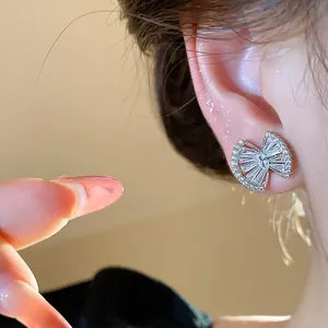 Detailed close-up showing a sparkling geometric zircon earring with 18k gold plating on a model's ear