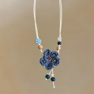Close-up of blue crochet flower necklace with wooden beads and sparkling rhinestone center