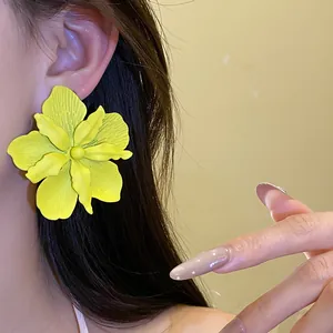 Close-up detail of a vibrant yellow spray-painted flower earring on the model's ear