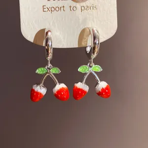 Detalle de los pendientes de aro con colgante de fresa roja y agujas de plata fina