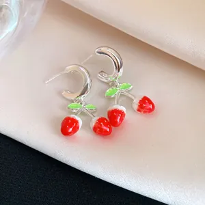 Vista macro de pendientes de fresa de esmalte con ganchos de aguja de plata finos