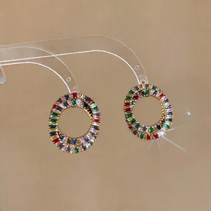Detailed close-up of vibrant multicolored zircon circular earrings on a clear stand