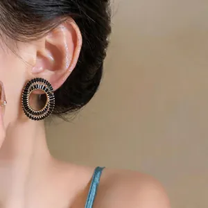 Detailed close-up shot of elegant oval stud earrings with black zircons worn by a model.