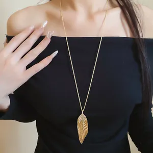 Elegant golden leaf pendant necklace with crystals on a long chain shown on a model