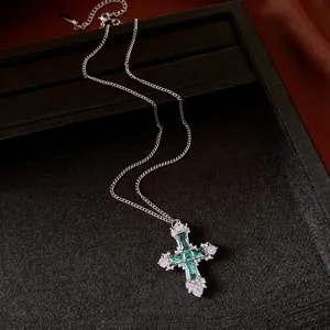 Elegant cross pendant necklace with emerald green stones and a silver link chain.