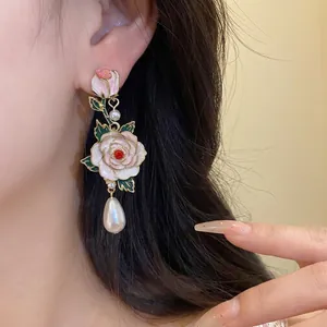 Boucles d'oreilles pendantes vintage en émail et perles sur l'oreille du modèle