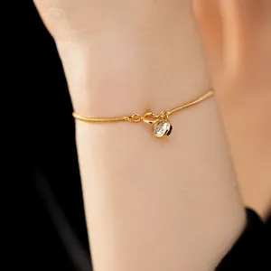 Detailaufnahme eines 18 Karat vergoldeten Schlangenarmbands mit rundem Zirkonia-Anhänger