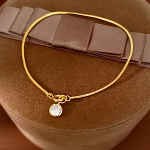 Detailansicht eines 18k vergoldeten Schlangenkettchen-Armbands mit rundem Zirkonia-Anhänger.