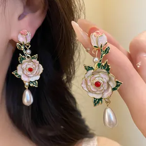 Gros plan de boucles d'oreilles vintage fleurs en émail, cristal rouge et perles