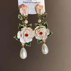 Détail de boucles d'oreilles roses vintage avec fleurs en émail et perles en poire