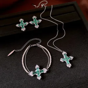 Detail view of emerald green cross jewelry set with pearls and silver chains.