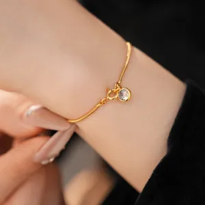 Nahaufnahme eines 18 Karat vergoldeten Armbands mit funkelndem runden Zirkonia-Anhänger.